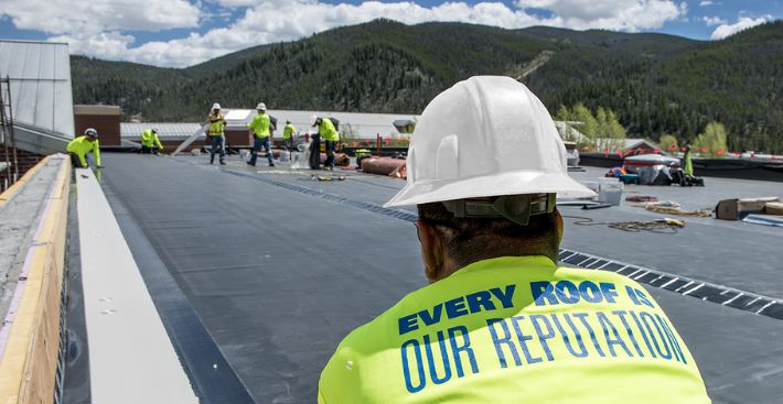 Roofer laying down EPDM membrane