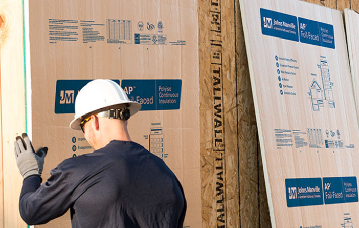Construction worker installing AP Foil on a wall
